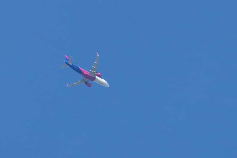 Airbus A321 jet aircraft of Wizz Air airlines in flight in a blue sky, England, United Kingdom