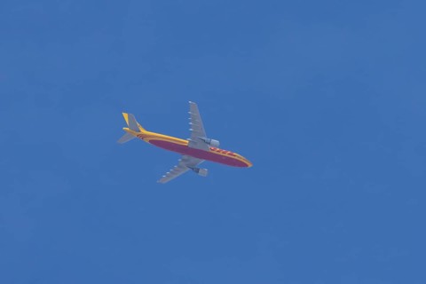 Boeing 767 jet aircraft of DHL cargo airlines in flight in a blue sky, England, United Kingdom