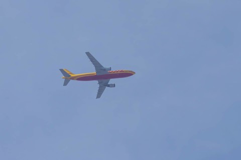 Boeing 767 jet aircraft of DHL cargo airlines in flight in a blue sky, England, United Kingdom