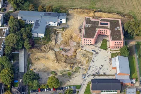 Aerial view, Pink building of the Reinoldi comprehensive school and construction site in the