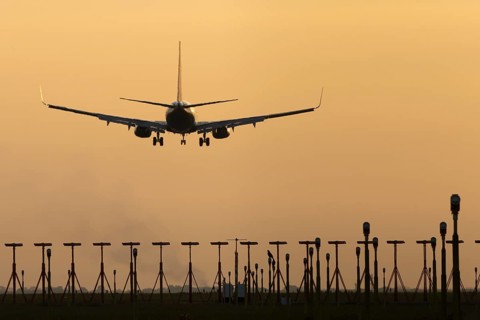 Boeing 737 jet passenger aircraft of Ryanair airlines landing over runway lights at sunset, London