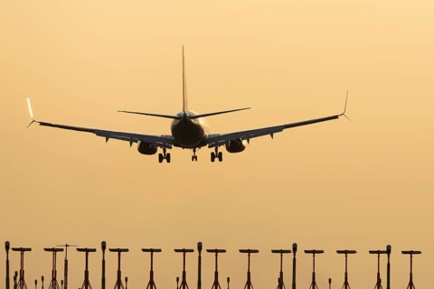 Boeing 737 jet passenger aircraft of Ryanair airlines landing over runway lights at sunset, London