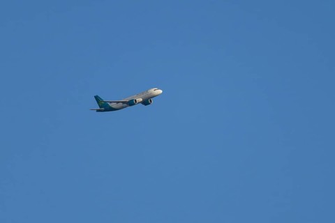 Airbus passenger jet aircraft of Aer Lingus flying in a blue sky, England, United Kingdom