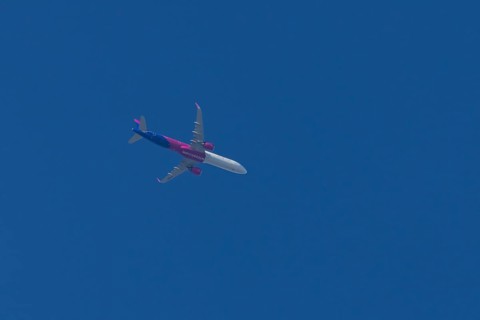 Airbus A321 jet aircraft of Wizz Air airlines in flight in a blue sky, England, United Kingdom