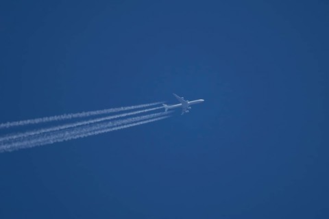 Airbus A340-300 jet aircraft of Lufthansa airlines in flight in a blue sky with vapour trails or