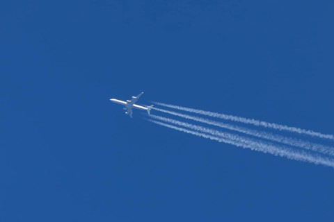 Airbus A340-300 jet aircraft of Lufthansa airlines in flight in a blue sky with vapour trails or