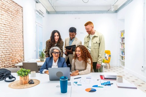 Diverse business team is collaborating and actively discussing financial data shown on a laptop