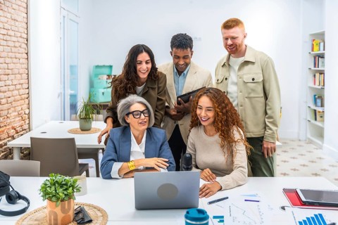 Multigenerational and diverse business team members working together, discussing ideas, and looking