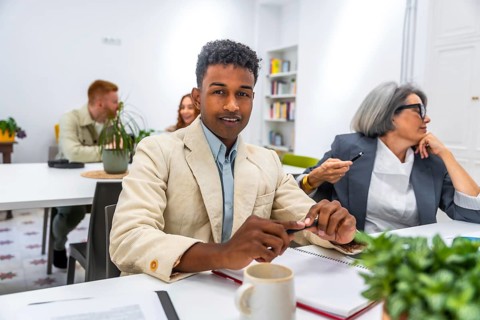 Young african american man smiling at the camera during a business meeting, with other diverse