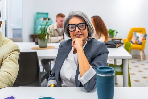 Experienced senior businesswoman smiling confidently during a meeting in a modern office,