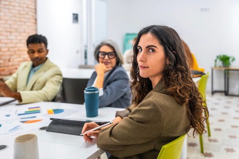 Young businesswoman with curly hair is looking back at the camera while attending a business