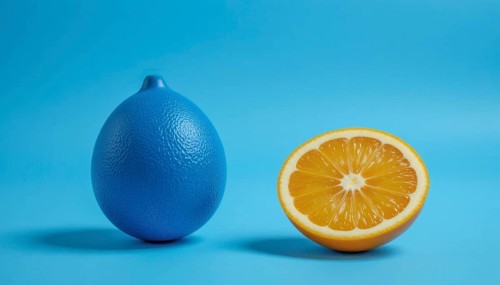 A vibrant image showcasing a blue lemon next to a half-cut orange, set against a bright blue