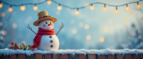 A charming snowman, adorned with a hat and scarf, stands on a snow-covered brick wall, illuminated