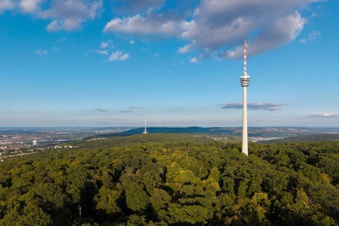 Modern television tower above a green forest and soft clouds in the blue sky, Stuttgart-Degerloch,