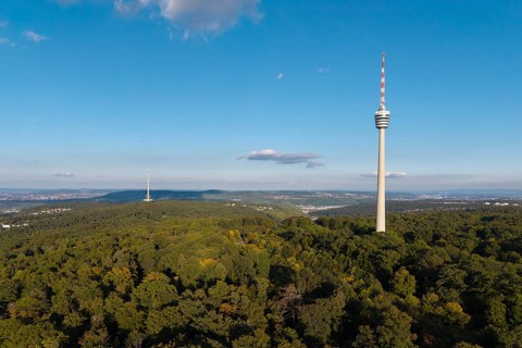 Sublime television tower above a green forest landscape with blue sky and clouds,