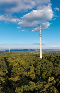 View of the television tower with dense forest and clear sky, soft clouds above,