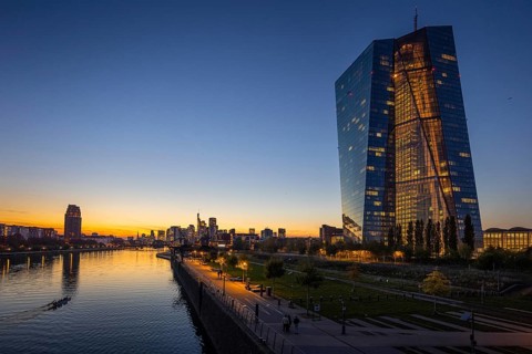 The lights of the European Central Bank (ECB) and the Frankfurt banking skyline glow in the