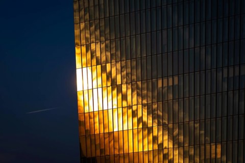 The light of the setting sun is reflected in the glass façade of the European Central Bank (ECB) in