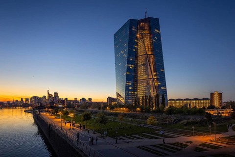 The lights of the European Central Bank (ECB) and the Frankfurt banking skyline glow in the