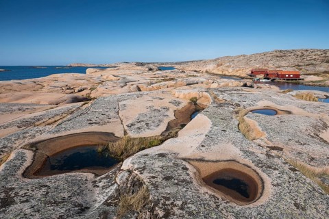 Rocks with rainwater puddles, falun red houses, rocky coast, Bohus granite, Ramsvik, nature reserve