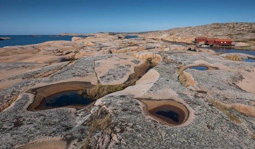 Rocks with rainwater puddles, falun red houses, rocky coast, Bohus granite, Ramsvik, nature reserve