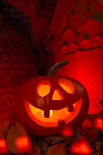 Halloween pumpkin with candlelight in the cemetery, illuminated red and spooky