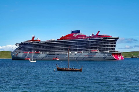 Large cruise ship next to a small Viking boat at sea, overtourism, Lerwick, Shetland Islands,