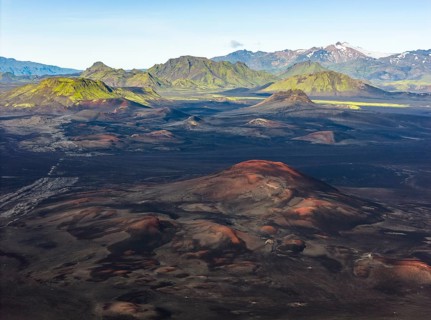 Volcanic landscape with black sand desert and red mountains, moss-covered mountains in the