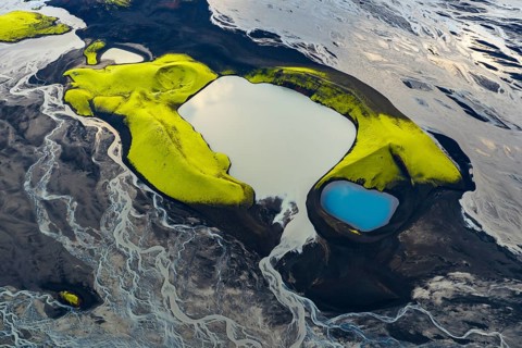 Turquoise-coloured crater lake with moss-covered crater rims in the Icelandic highlands, surrounded