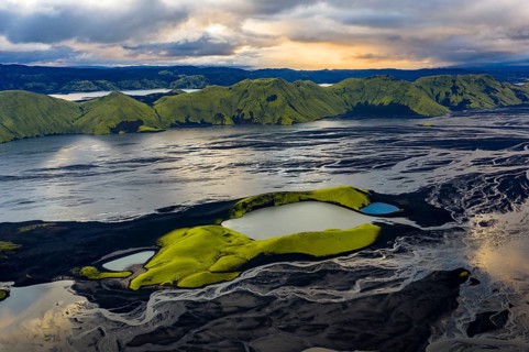 Turquoise-coloured crater lake with moss-covered crater rims in the Icelandic highlands, surrounded