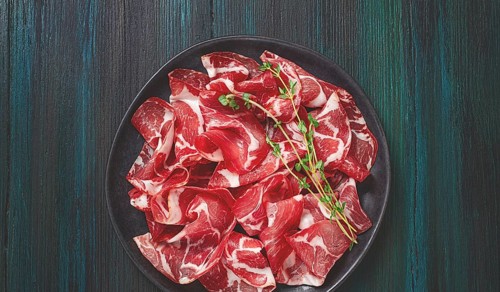 Plate with sliced cured meat, pork neck, prosciutto coppa, Italian delicacy