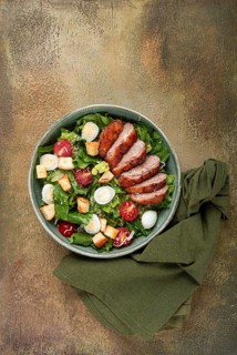 Caesar salad, with duck breast, on a green plate, homemade, no people