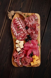 Assorted, sliced meat appetizer, prosciutto, salami and ham, with cheese and olives, on a wooden