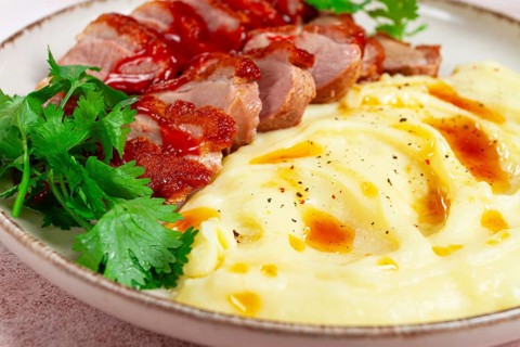 Roast duck breast, sliced with mashed potatoes, on a white plate, close-up, no people
