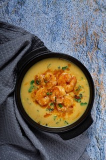 Creamy shrimp curry with spices, garnished with herbs, on a textured background, homemade, no