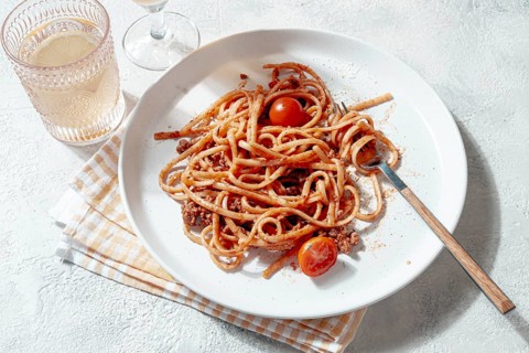 Freshly cooked spaghetti topped with savory meat sauce and garnished with cherry tomatoes is