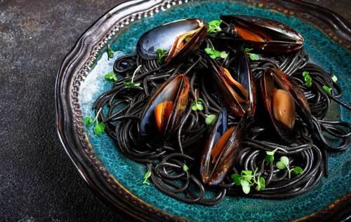Black spaghetti, nori pasta, with mussels, top view, on a dark background, homemade, no people