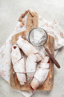 Bagels with filling, sweet pastries, sprinkled with powdered sugar, on a wooden board, dessert,