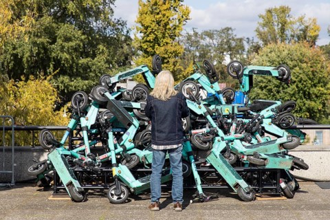 A man looks at an exhibit with stacked e-scooters on the roof terrace of the Haus der Kulturen der