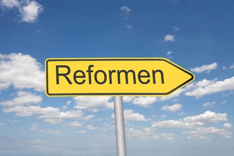(Photomontage) Directional arrow with the inscription REFORMEN in front of a blue sky