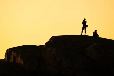 Silhouette of two tourists photographing the sunset on a rock, Smögen, Smögenbryggan, Västra