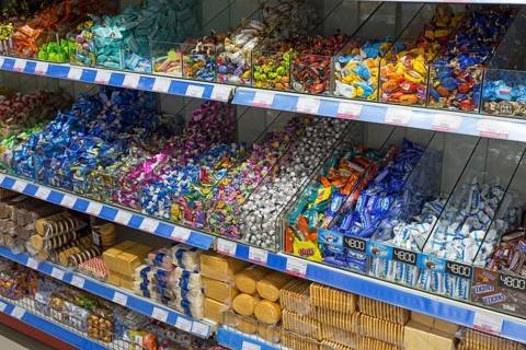 Shelves full of colourful candy wrappers and biscuits in a supermarket, affordable prices and