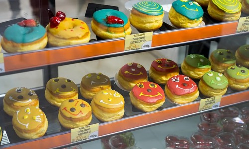 Donuts with colourful glazes and faces in a glass display, Gntunik supermarket, Aragazotn province,
