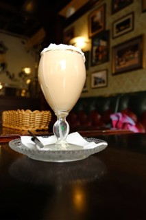 A coffee drink with whipped cream sits on a table in an English pub