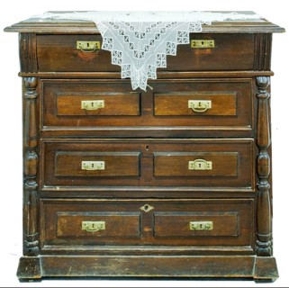 A vintage chest of drawers covered with an openwork crocheted doily