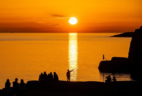 Silhouettes of tourists, sun melting in the sea, sunset, archipelago landscape, Smögen,