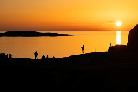 Silhouettes of tourists, sun melting in the sea, sunset, archipelago landscape, Smögen,