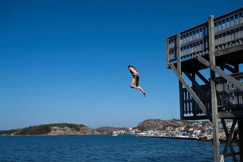 Girl jumping from a high wooden diving platform into the sea, lido, Fjällbacka, Bohuslän, West