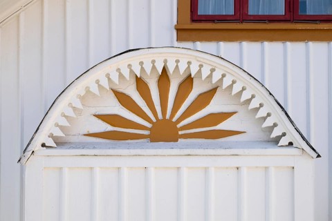 Detail of an ornament symbolising the sun in yellow and white on a wooden house, Fjällbacka,