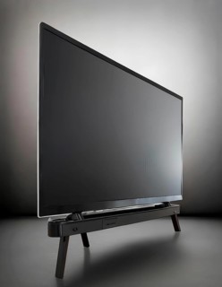 A black flat screen television is turned off. The stand is black and has a black base, AI generated